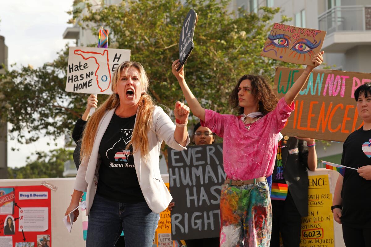 Two people hold up picket signs protesting book bans in Florida.