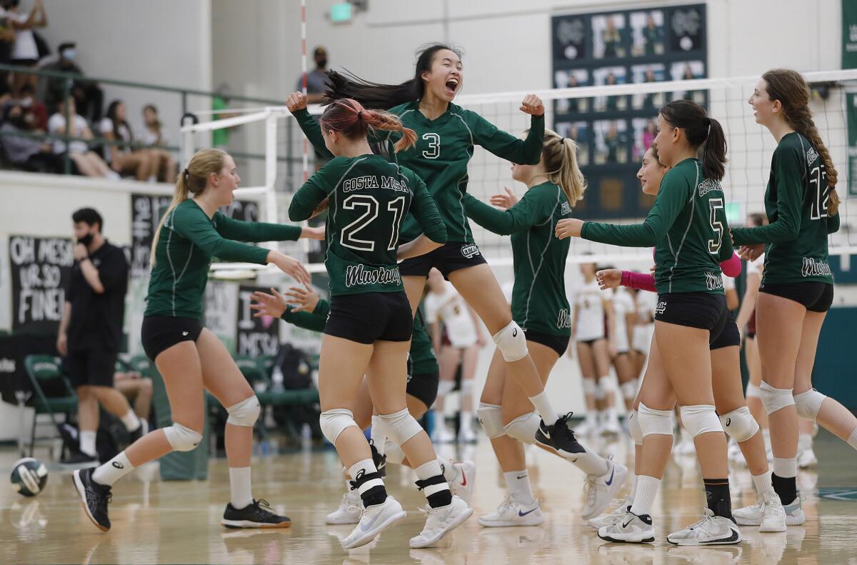 The Costa Mesa girls' volleyball team celebrates winning the third set against Estancia on Thursday.