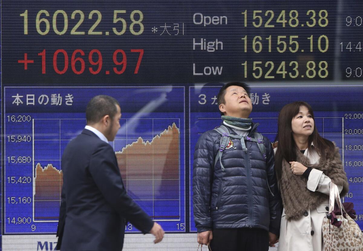 A couple stand by an electronic stock board of a securities firm in Tokyo, Monday, Feb. 15, 2016. Japanese stocks rocketed Monday, leading most Asian markets higher after dismal growth data raised hopes of extra stimulus for the world's third-biggest economy, weakening the yen.