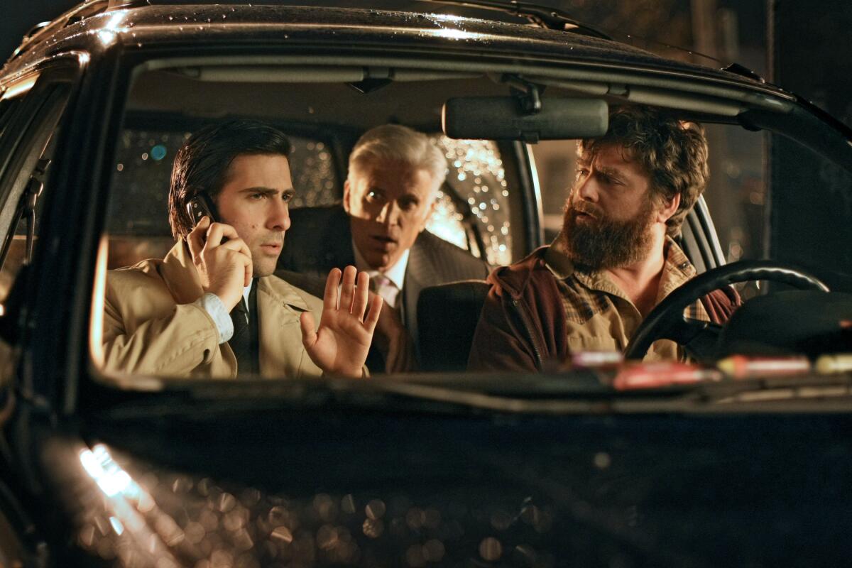 Two men sitting in the front seat of a car with another in the back seat.