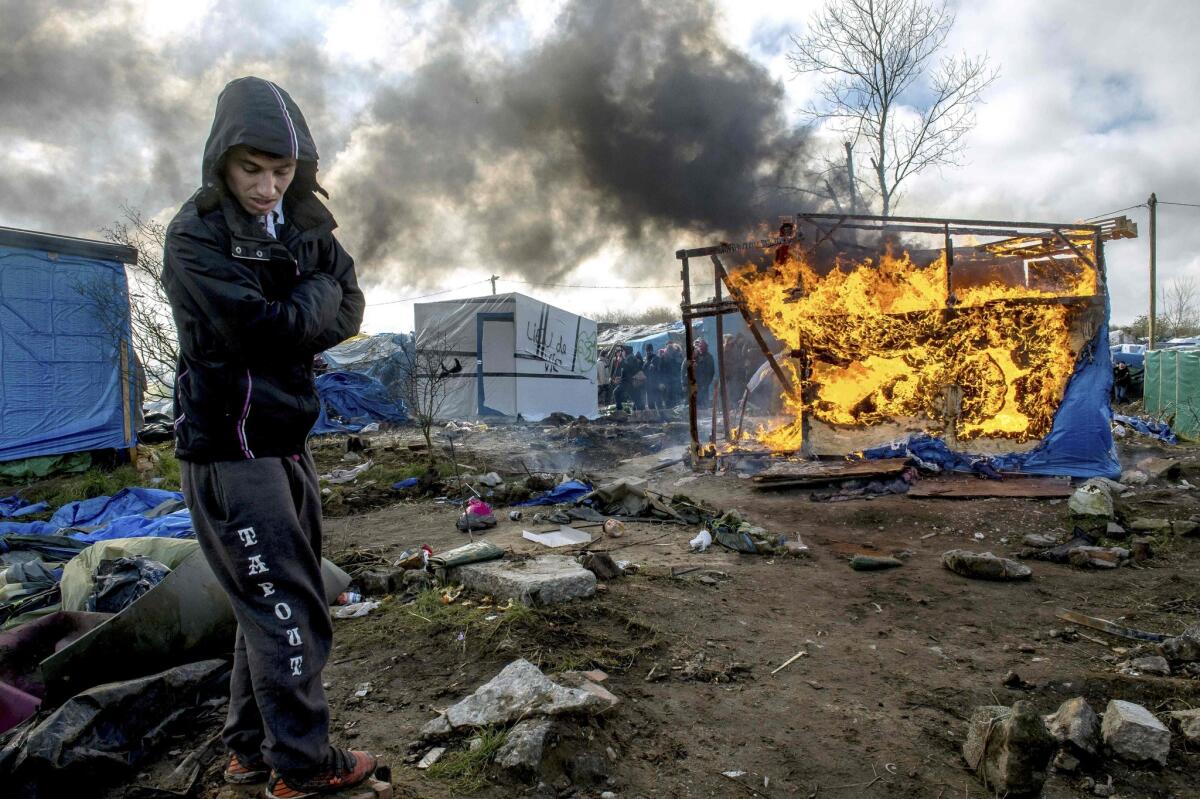 A man stands by as a makeshift shelter burns in the so-called Jungle migrant camp in the French port city of Calais on Thursday.