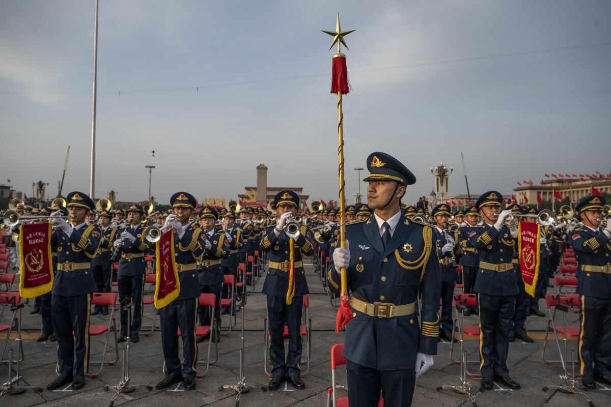 A band conductor stands in front of band members at a ceremony marking the 100th anniversary of the Communist Party 