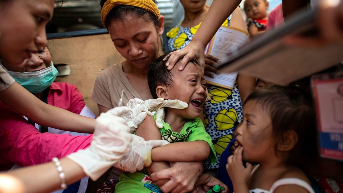 A Philippine Red Cross worker administers a measles vaccine in Manila.