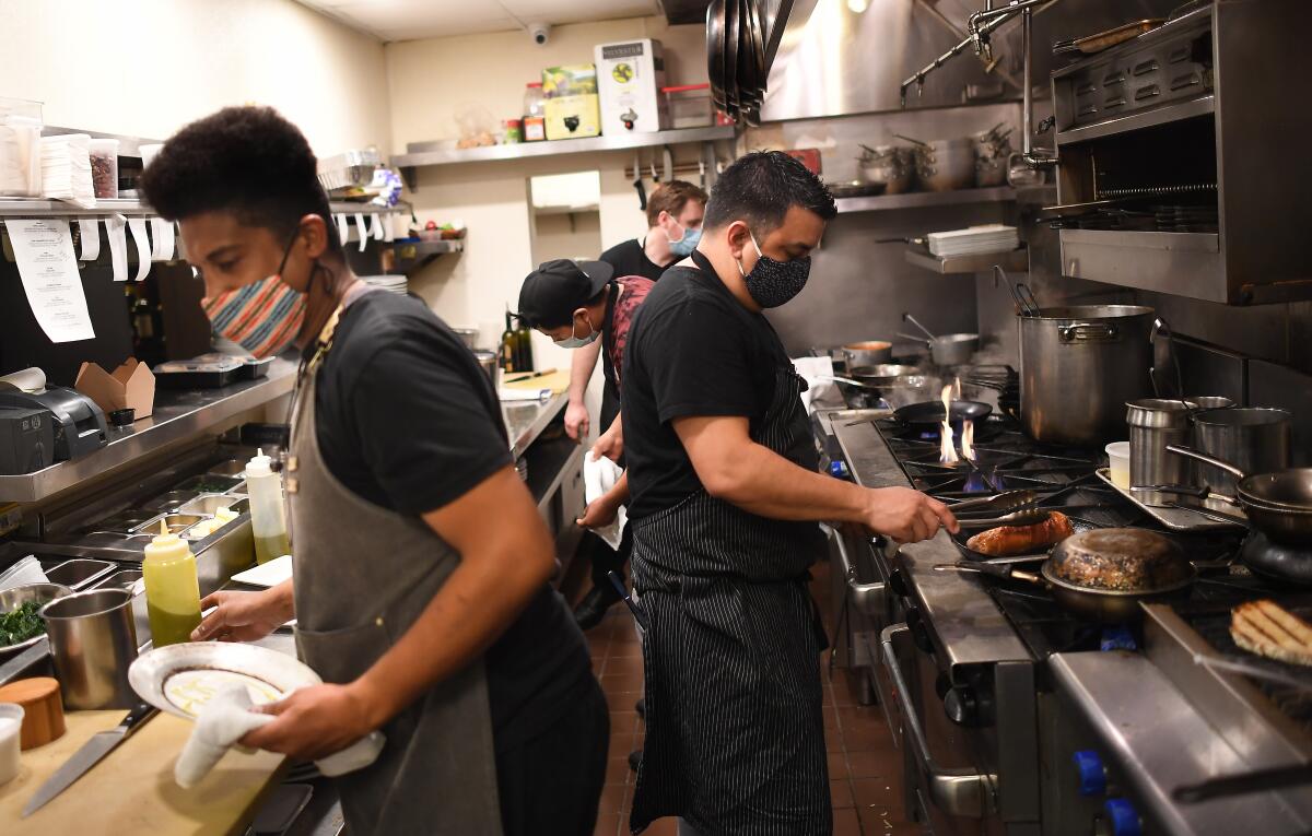 Chef Eric Samaniego, right, and others work in a kitchen.