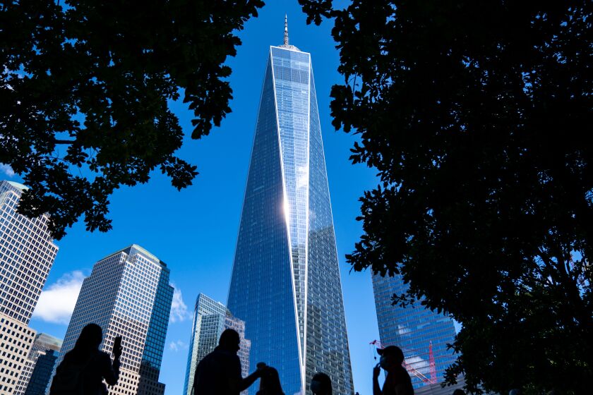 NEW YORK, NY - SEPTEMBER 03: One World Trade Center is framed by trees near the South Reflecting pool as people visit the September 11 Memorial at Ground Zero on Friday, Sept. 3, 2021 in New York, NY. New York City and much of the nation are preparing for the 20th anniversary of the terrorist attacks in both New York City and Washington DC. (Kent Nishimura / Los Angeles Times)
