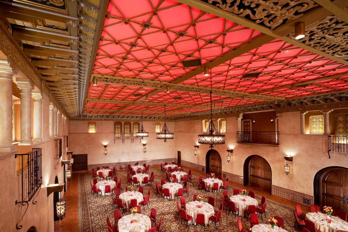 A ballroom with an illuminated red ceiling trimmed in gold.
