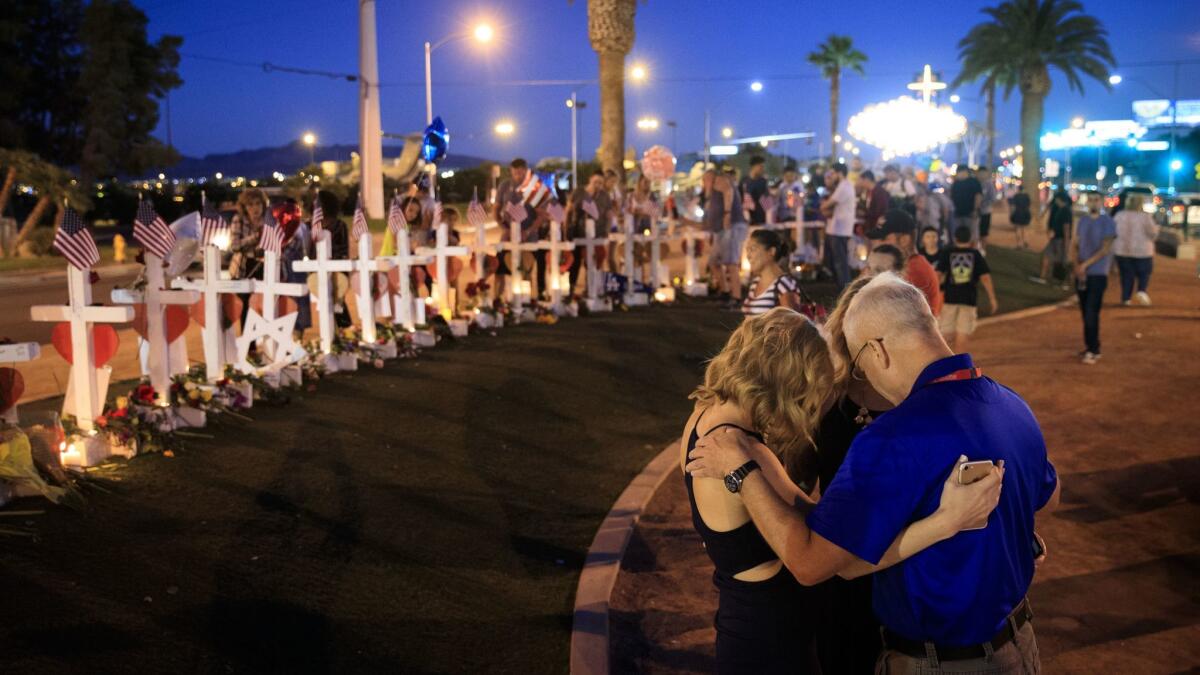 Some visitors pay at the temporary memorial with 58 white crosses, one for each victim, on the south end of Las Vegas Strip,