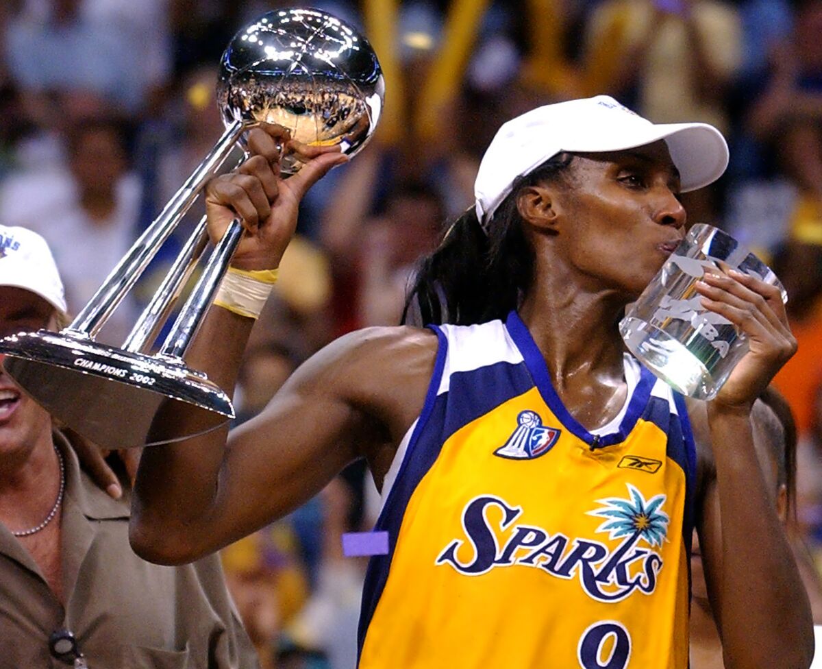 Sparks' Lisa Leslie kisses her MVP trophy and holds up the championship trophy.