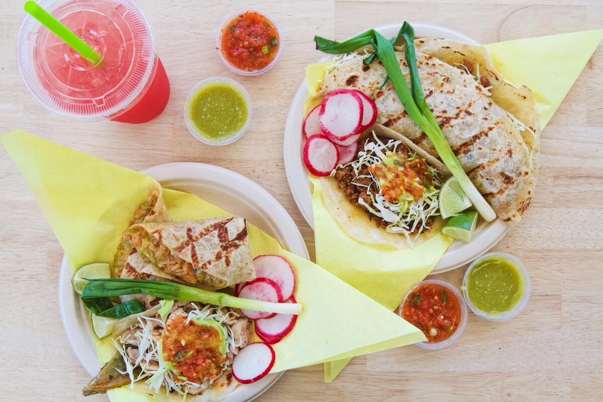 An overhead photo of watermelon agua fresca and two plates from Sonoratown, featuring tacos, a chivichanga and a caramelo. 