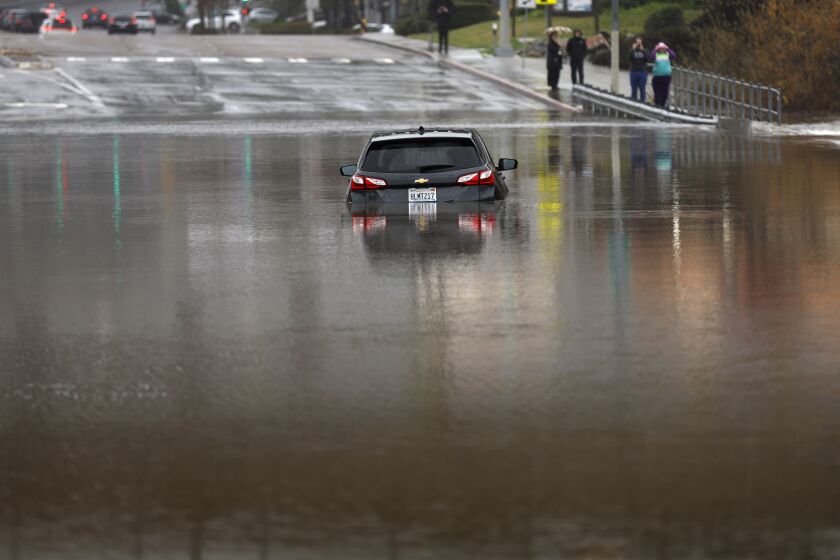 San Diego CA - January 16: A car was submerged on a flooded Mission Center Road at the San Diego River in Mission Valley on Monday, January 16, 2023. (K.C. Alfred / The San Diego Union-Tribune)