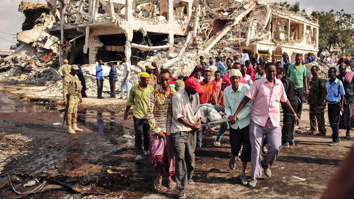 Men carry away a victim who died in the explosion of a truck bomb in Mogadishu, Somalia, on Oct. 14, 2017.
