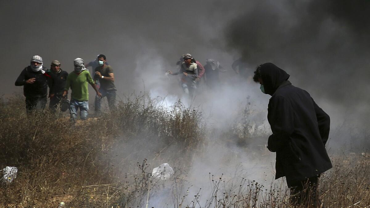 Palestinian protesters run from tear gas fired by Israeli troops after they burned tires during a protest at the Gaza Strip's border with Israel on Friday.