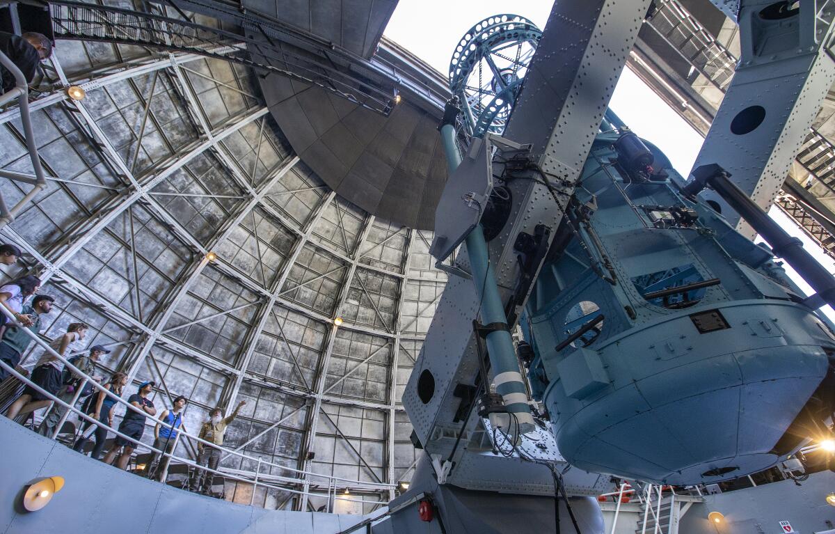 Docent Tim Thompson, right, gives students from USC a tour inside the 100-inch telescope at Mt. Wilson Observatory.