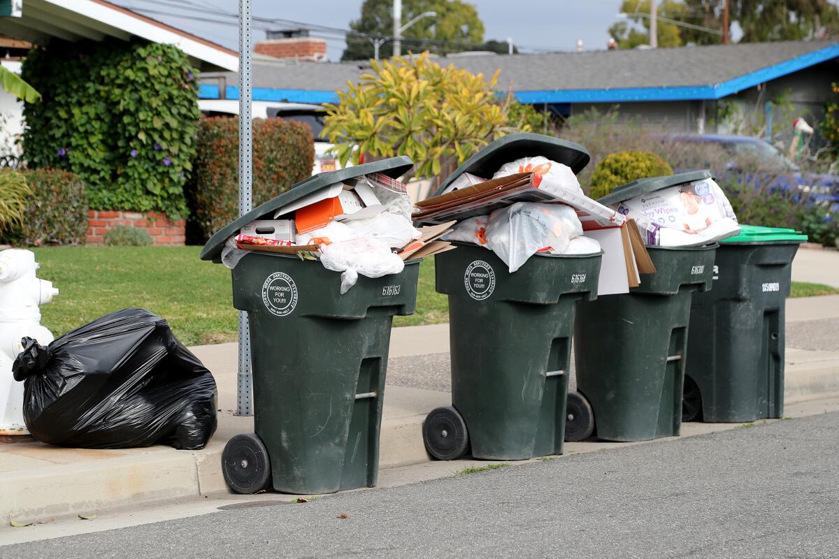 Trash cans overflowing with garbage on Tuesday along Hanover Drive in Costa Mesa.