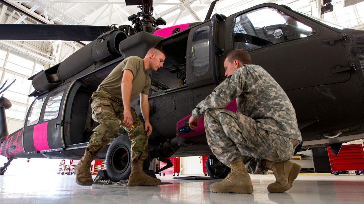 Spc. Jesse Lambert, left and Spc. Daniel Cooper work on a California National Guard UH-60 Black Hawk helicopter that assisted in fighting fires in Ventura County.