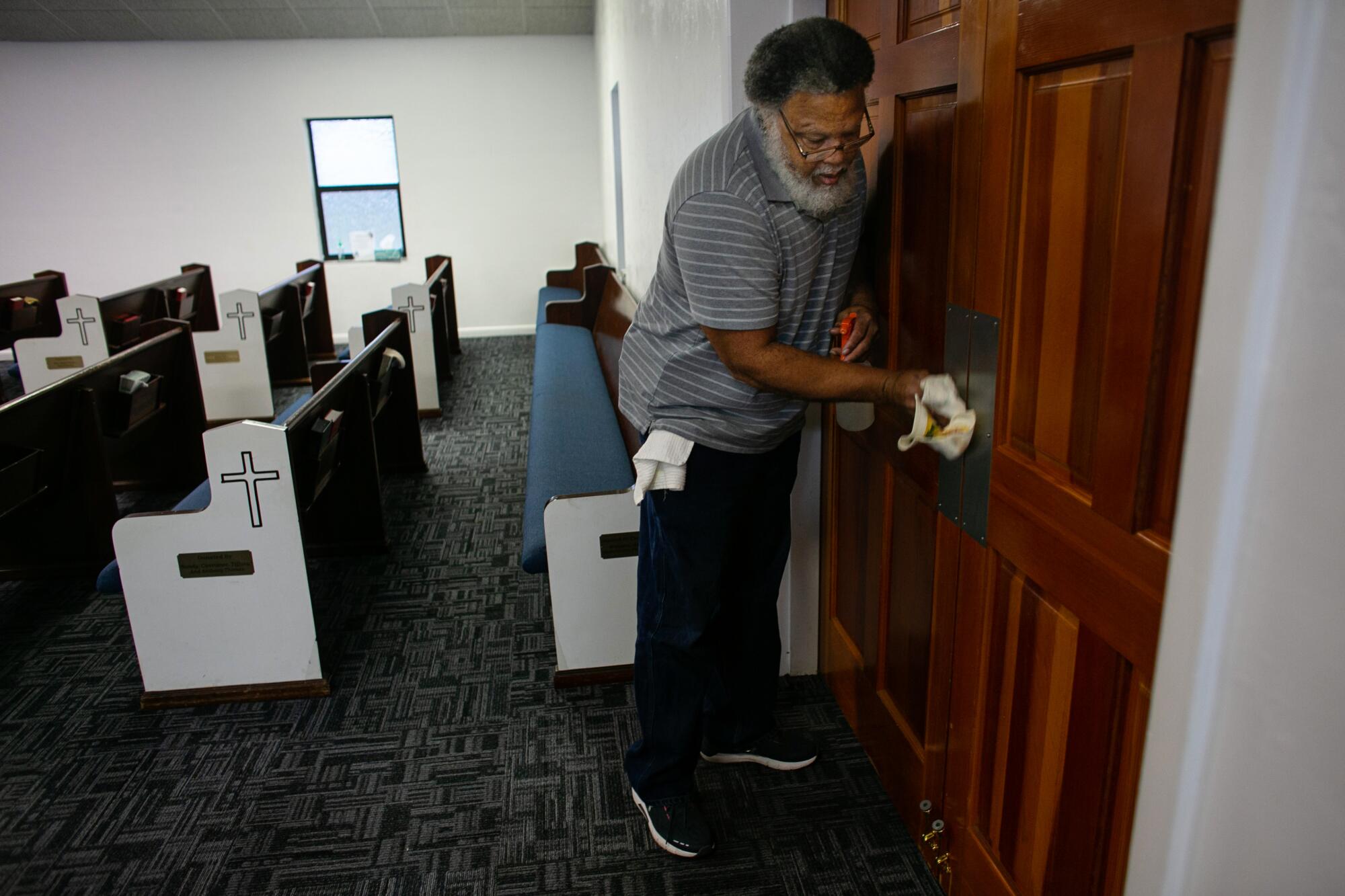 El pastor Albert Mann desinfecta las puertas que conducen al santuario de su iglesia.
