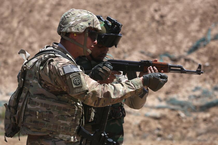 A U.S. Army trainer, left, instructs an Iraqi military recruit at a base in Taji on April 12, 2015.