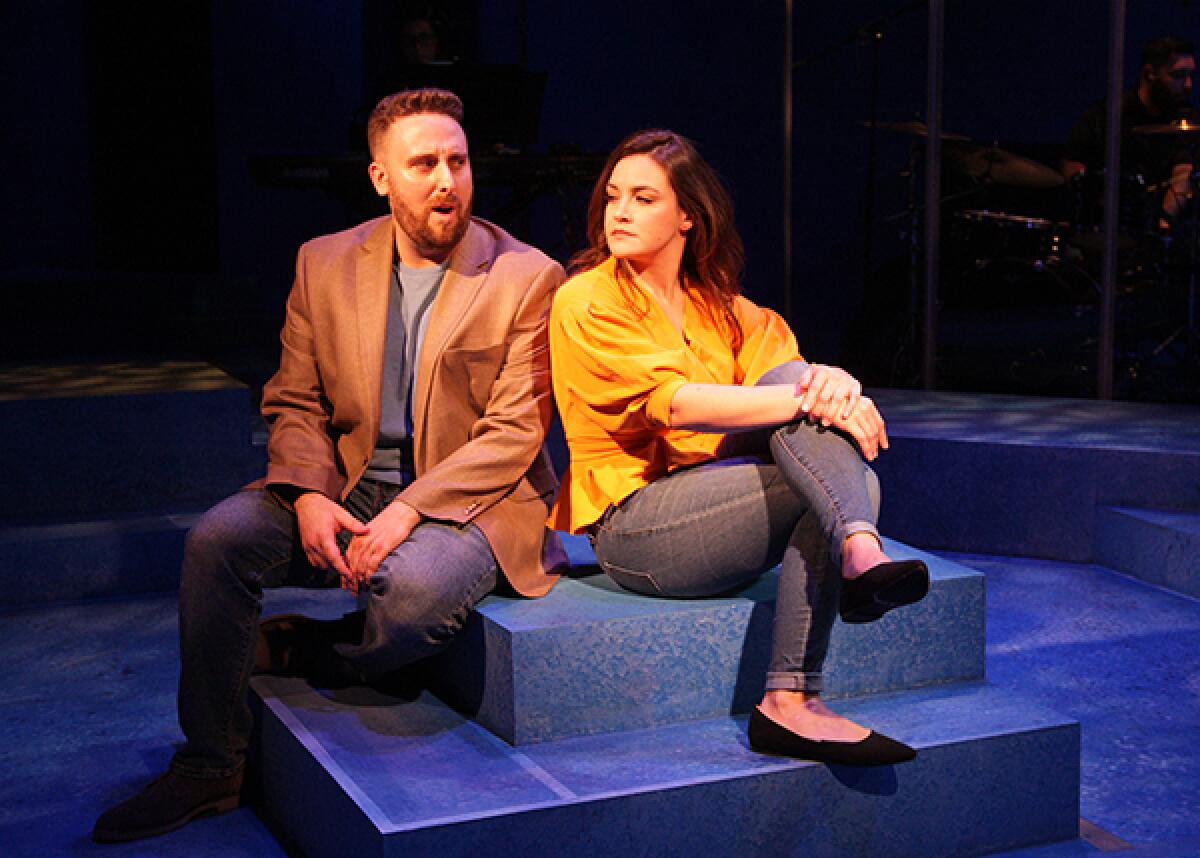 A singing man and woman exchange knowing looks on a stage