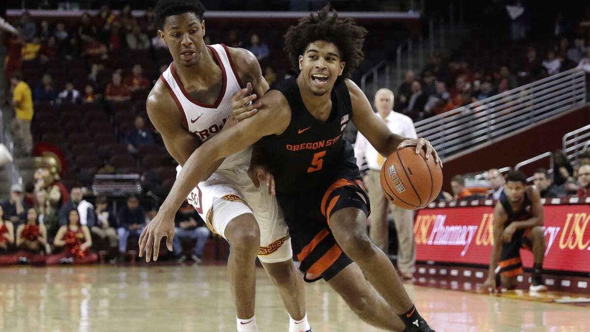 Oregon State 's Ethan Thompson, right, is defended by USC's Elijah Weaver, left, during the first half on Saturday at Galen Center.