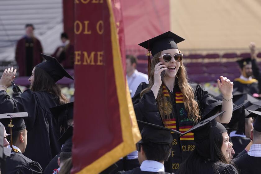 ARCHIVO - Una alumna que concluyó sus estudios en la Universidad de Boston habla por teléfono durante la ceremonia de graduacion, el 22 de mayo de 2023, en Boston. (AP Foto/Steven Senne, archivo)