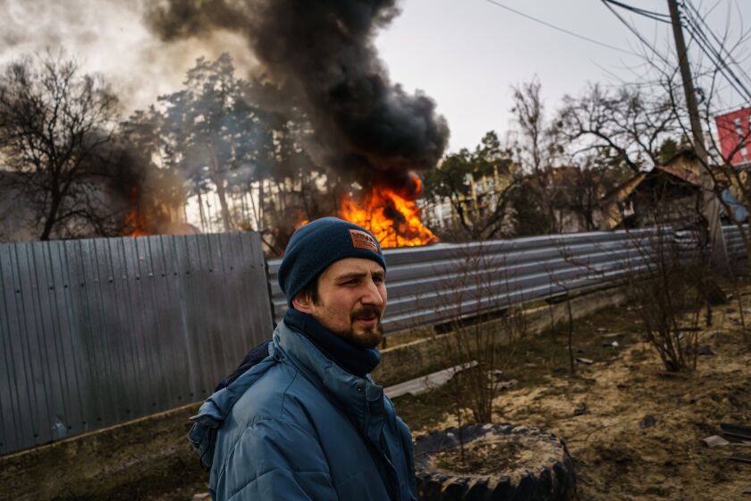 IRPIN, UKRAINE -- MARCH 12, 2022: Maksim Chepchenko assess his surroundings after making sure nobody was left behind in a home ablaze after Russian bombardment, in Irpin, Ukraine, Saturday, March 12, 2022. (MARCUS YAM / LOS ANGELES TIMES)