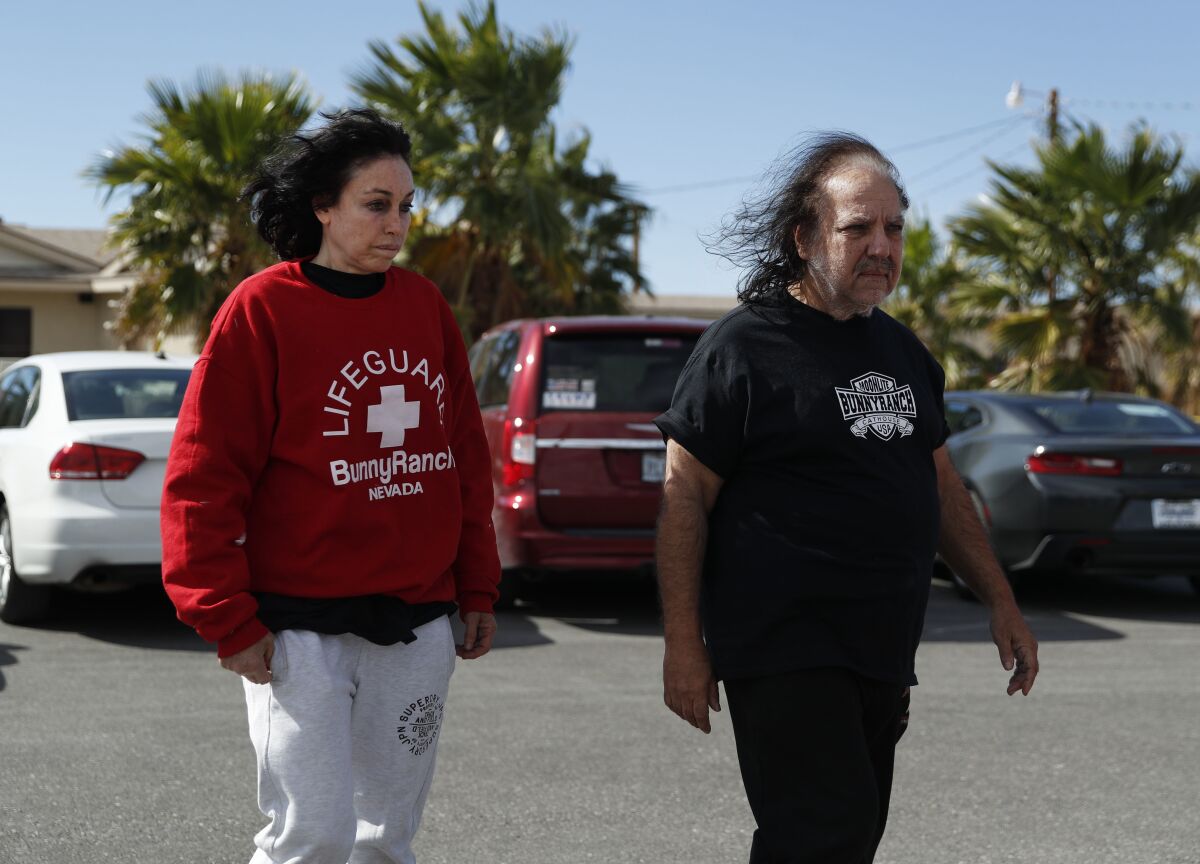 FILE - Ron Jeremy, right, and Heidi Fleiss walk out of the Love Ranch brothel, Tuesday, Oct. 16, 2018, in Pahrump, Nev. The woman dubbed the "Hollywood Madam" when she was accused in the mid-1990s of running a high-priced Los Angeles prostitution ring says she's moving out of the southern Nevada town where she's lived for about 15 years. (AP Photo/John Locher,File)
