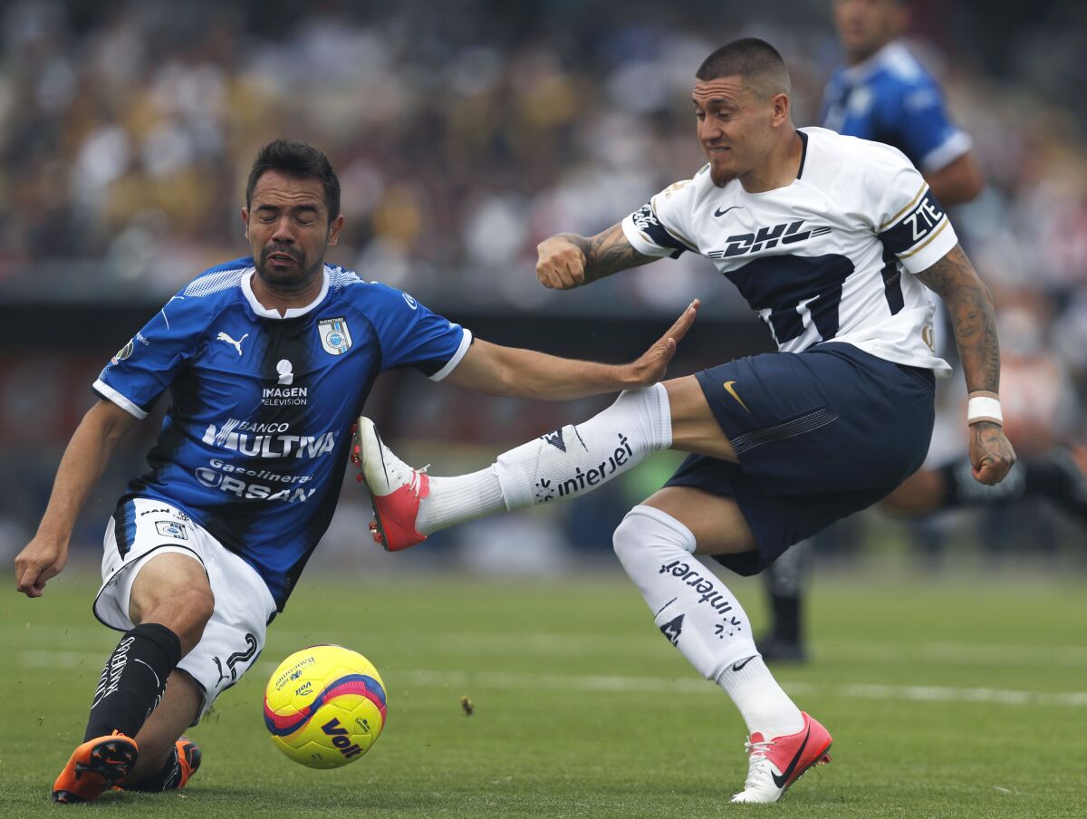 Queretaro's Josecarlos Van Rankin, left, blocks Pumas' Nicolas Castillo during a Mexican soccer league match in Mexico City, Sunday, April 29, 2018. Pumas and Queretaro tied 1-1.