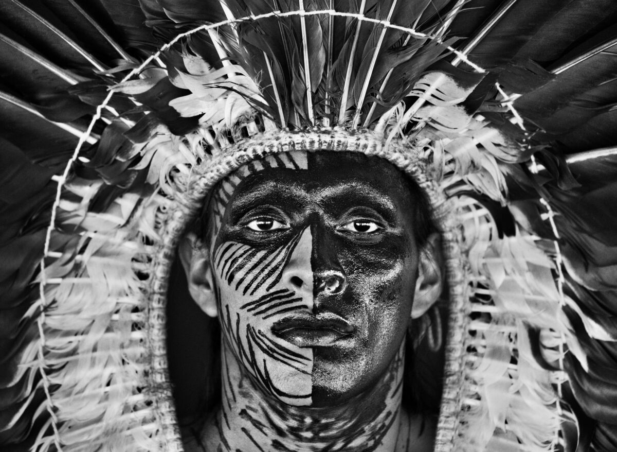 Adao Yawanawa in a headdress of eagle feathers, wearing face paint made from the fruit of the genip tree 