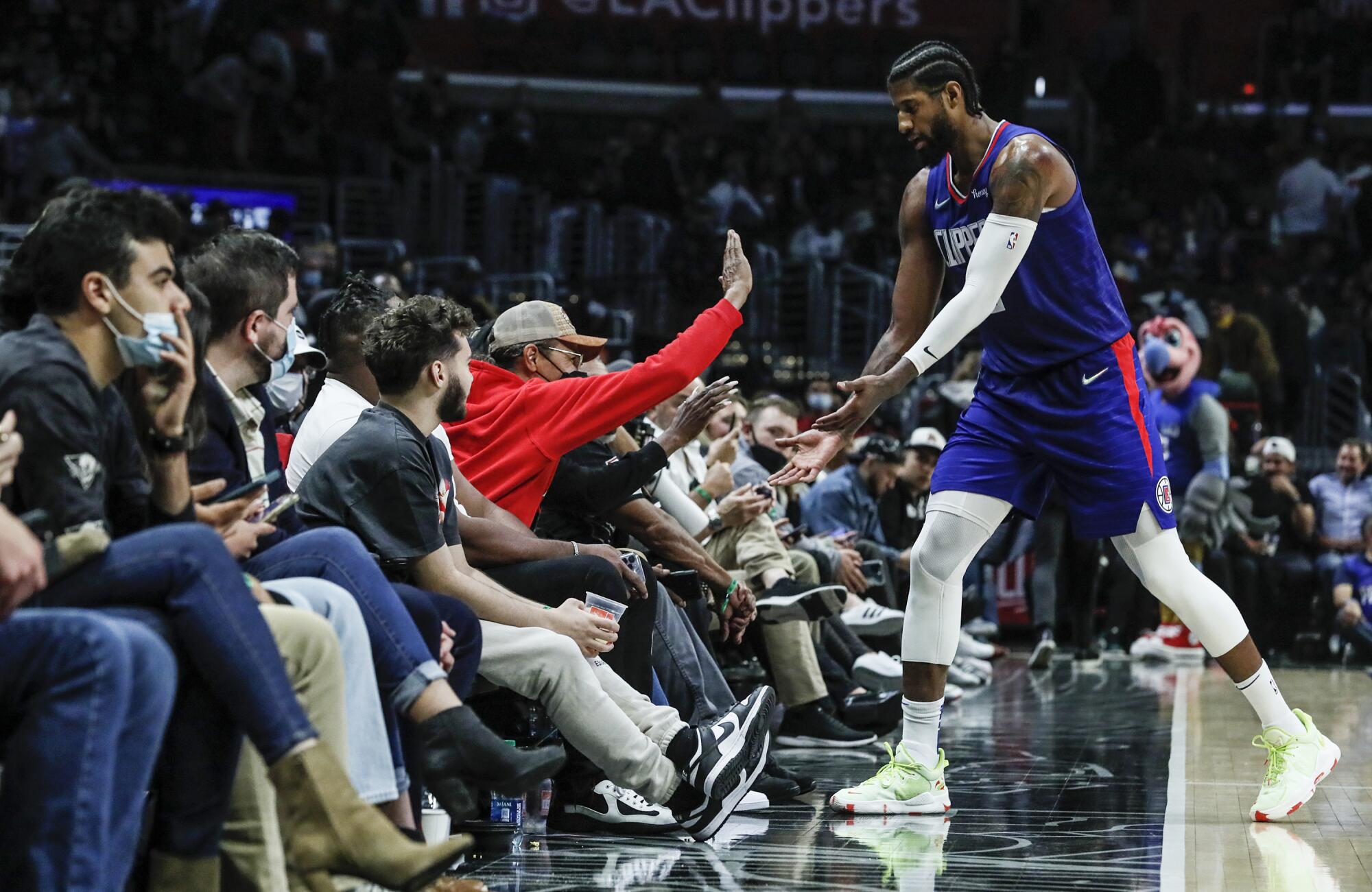 Clippers forward Paul George  slaps hands with a fan.