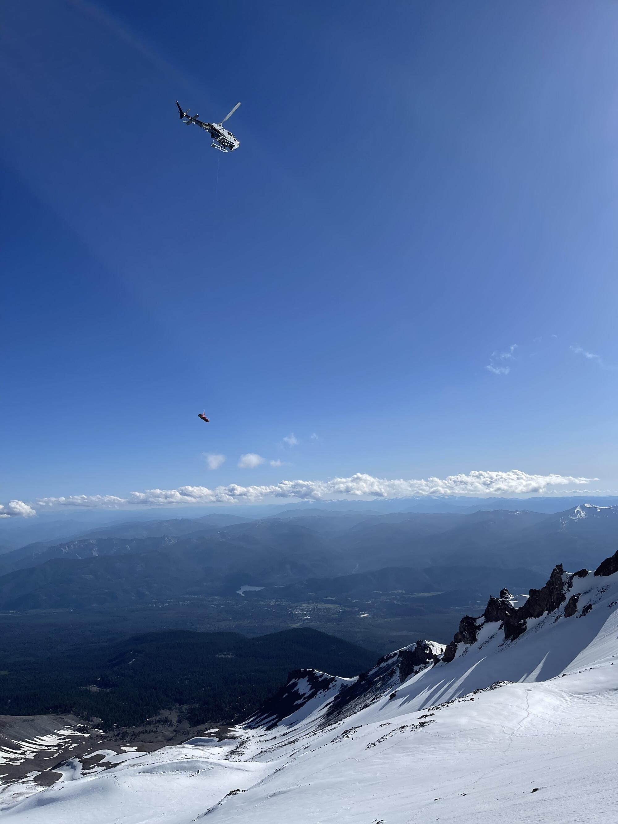 A helicopter hovers over a snowy slope