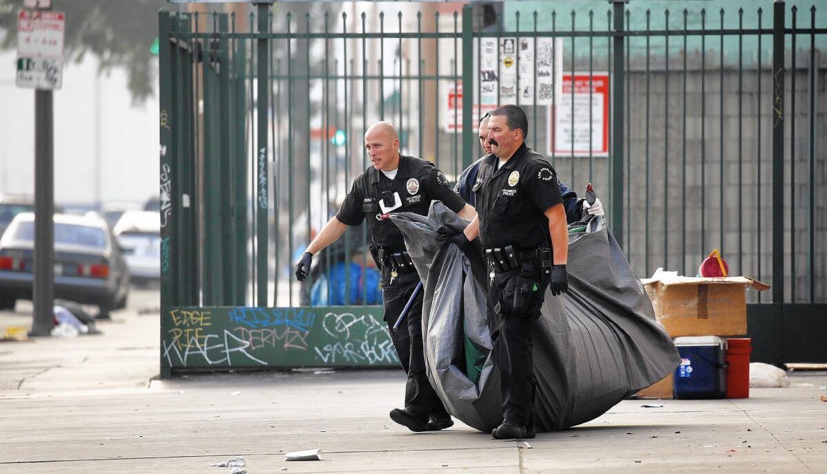 Los Angeles police officers remove belongings at 4th and San Pedro streets in downtown Los Angeles.