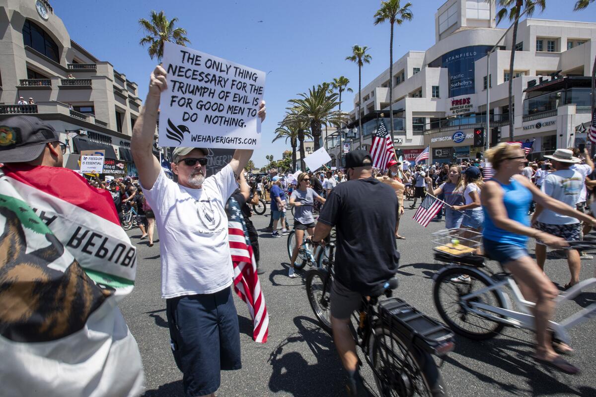 Protesters refuse to practice social distancing while crossing the street at Main Street and Pacific Coast Highway in Huntington Beach on Friday.