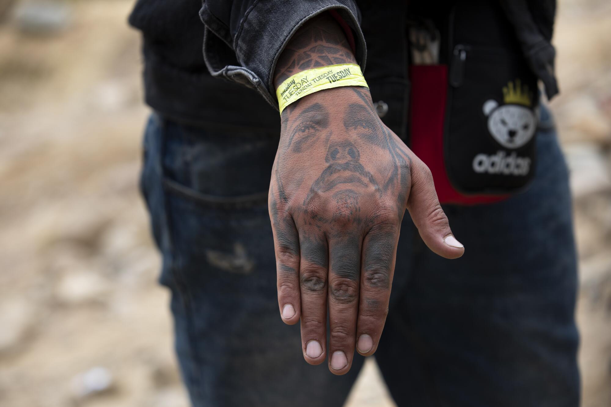 A man with a wristband of when he arrived waits between the border walls that separate Tijuana from San Diego.