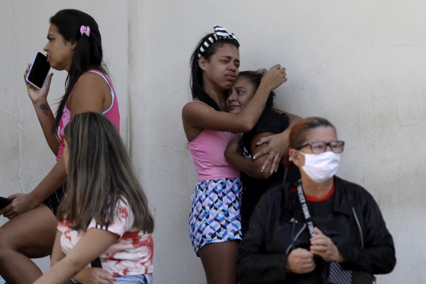 People wait outside a hospital for the arrival of people who were injured or killed during a police raid.