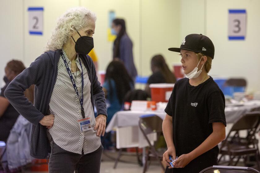 Barbara Ferrer, Director of Public Health, talks with Ryder McReynolds, 11, after Ryder got his COVID-19 booster shot at a vaccination clinic hosted by Los Angeles County Public Health at Balboa Sports Complex in Encino, Calif., on Saturday May 21, 2022. COVID-19 booster shots are now available for children ages 5-11 in Los Angeles County and LA County Public Health is encouraging parents to bring eligible children to vaccination sites to get boosted before summer vacation and holiday travel. Ryder's grandmother Kirsten Thye, not pictured, said she decided to bring Ryder today so he'd be extra protected for all of the summer activities coming up. (Alisha Jucevic/For The Times)