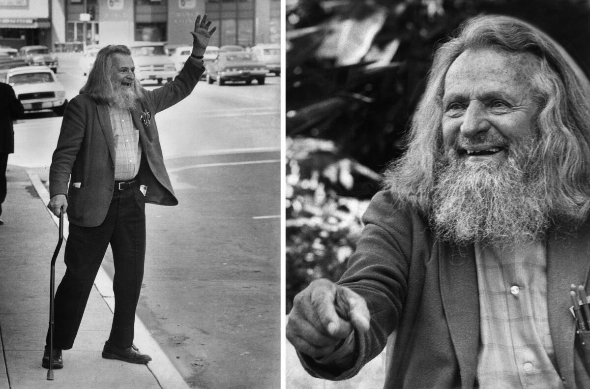 A man with a beard stands on the sidewalk and waves