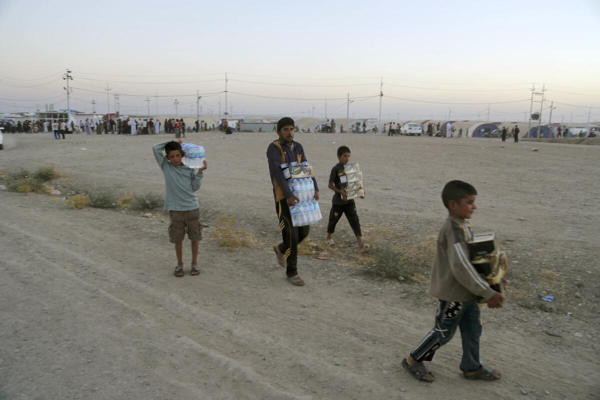 Displaced Iraqis from the Yazidi community carry humanitarian aid at the camp of Bajid Kandala at Feeshkhabour town.