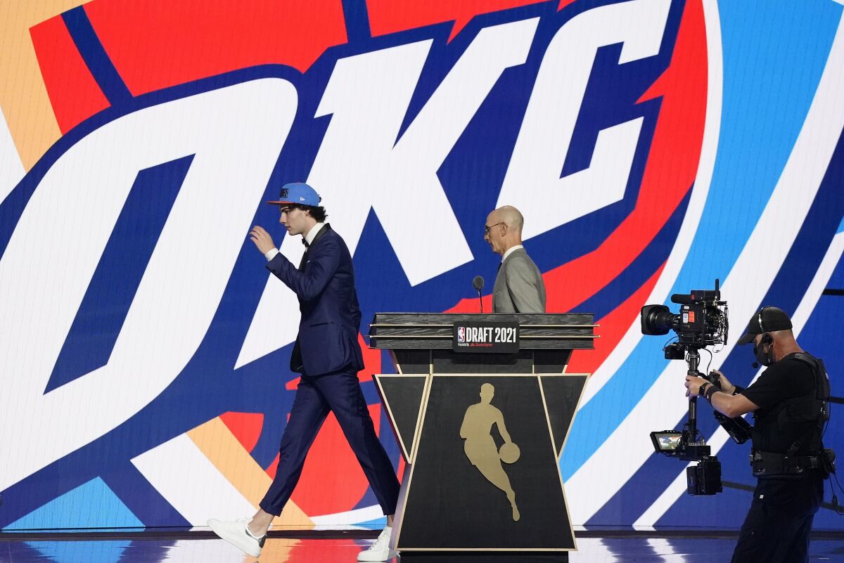 CORRECTS SPELLING TO GIDDEY, INSTEAD OF GIDDY - CORRECTS TEAM TO OKLAHOMA CITY THUNDER, INSTEAD OF GOLDEN STATE WARRIORS - Josh Giddey, left, walks off the stage with NBA Commissioner Adam Silver after being selected sixth overall by the Oklahoma City Thunder during the NBA basketball draft, Thursday, July 29, 2021, in New York. (AP Photo/Corey Sipkin)