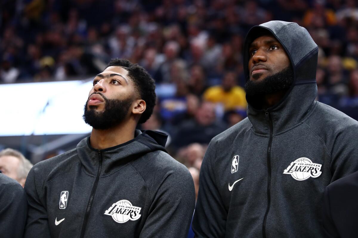 Lakers forwards Anthony Davis and LeBron James watch the Lakers play a game from the bench earlier this season.