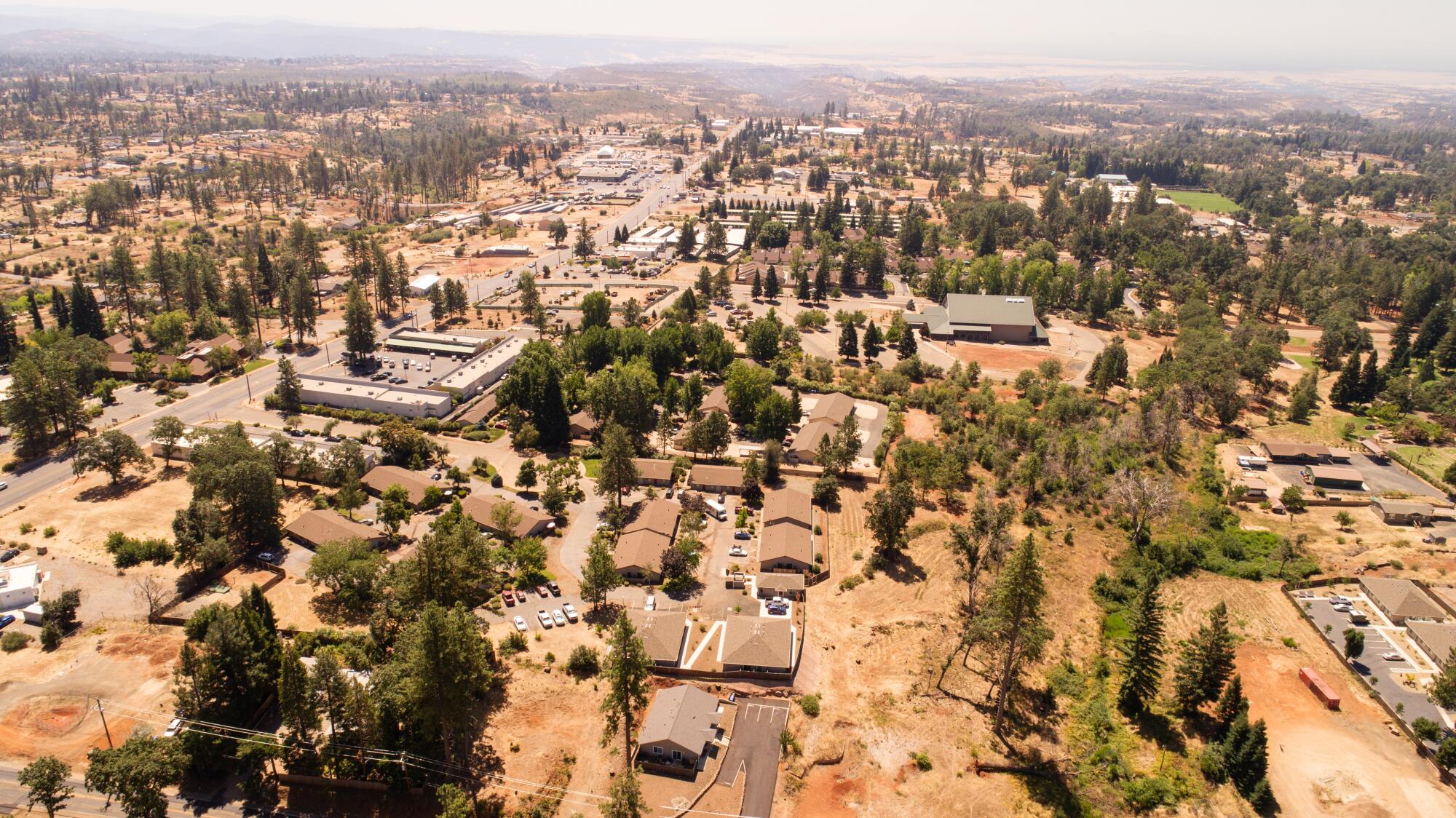 An aerial view of commercial buildings in a wooded locale.