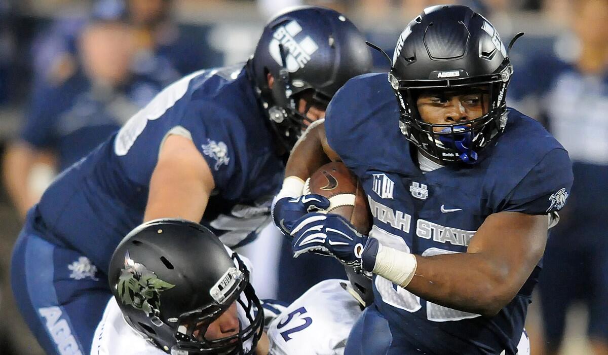 Utah State running back Devante Mays runs past Weber State defensive end Jonah Williams and defensive tackle Rayshawn Henderson (52) during a game Sept. 1.