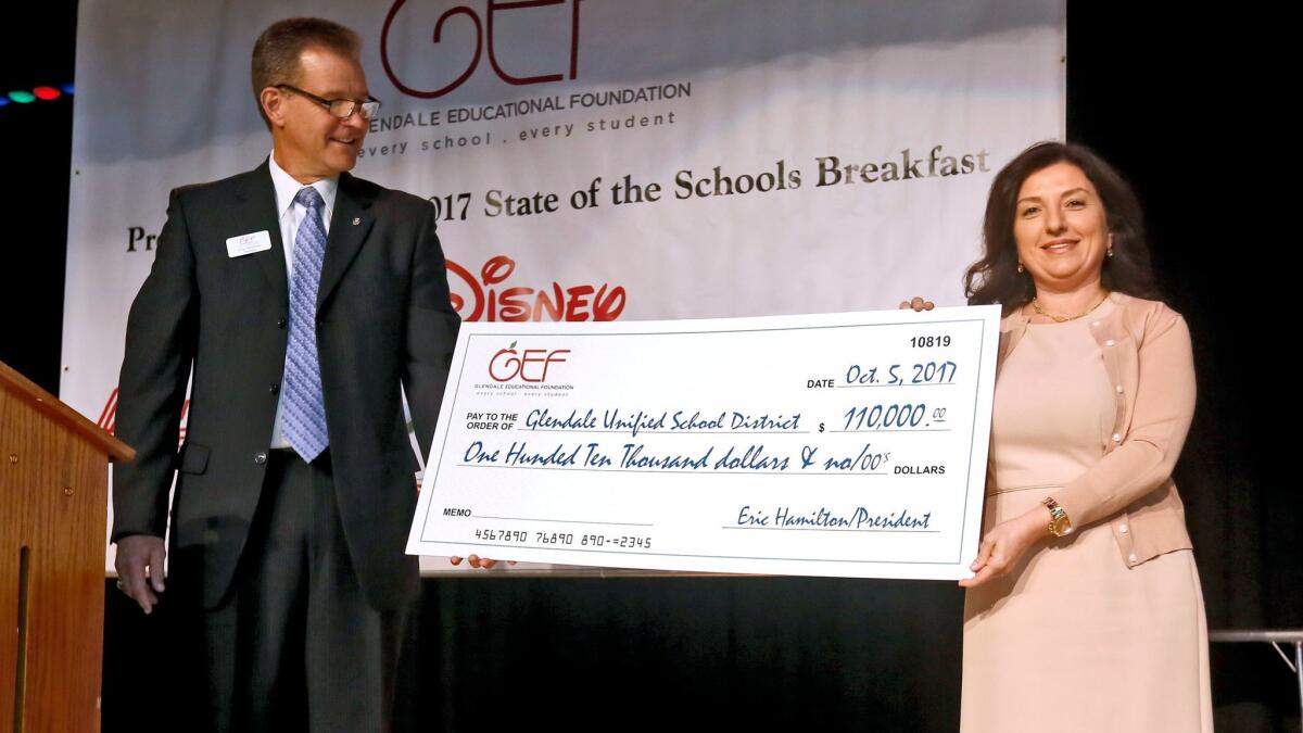 Glendale Education Foundation's Eric Hamilton, left, gives a check for $110,000 to GUSD's school board president Nayiri Nahabedian at the 13th annual State of the Schools Breakfast on Thursday, Oct. 5.
