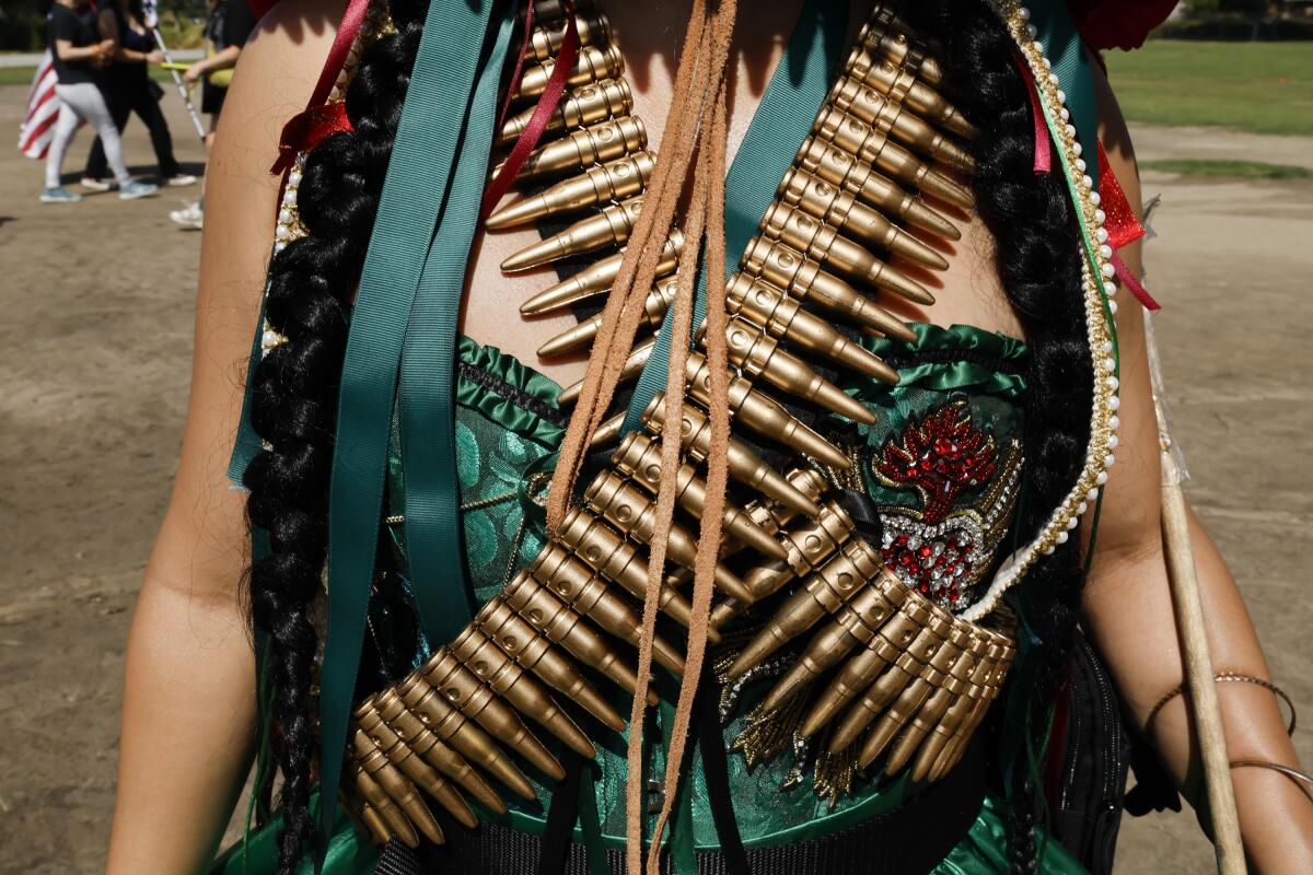 Los Angeles, CA - July 04: Nancy Gonzalez wears fake bullet belts with her ornate dress made by Maria Flores representing Mexico at a rally against the ongoing ICE raids taking place in the city at LA City Hall on Friday, July 4, 2025 in Los Angeles, CA. (Carlin Stiehl / Los Angeles Times)