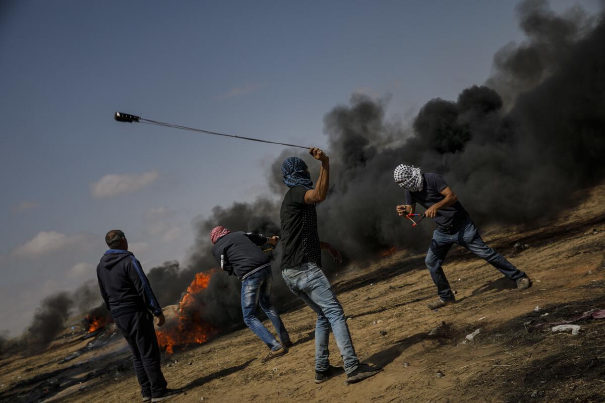 Palestinians aim projectiles towards the border fence separating Israel and the Gaza Strip.