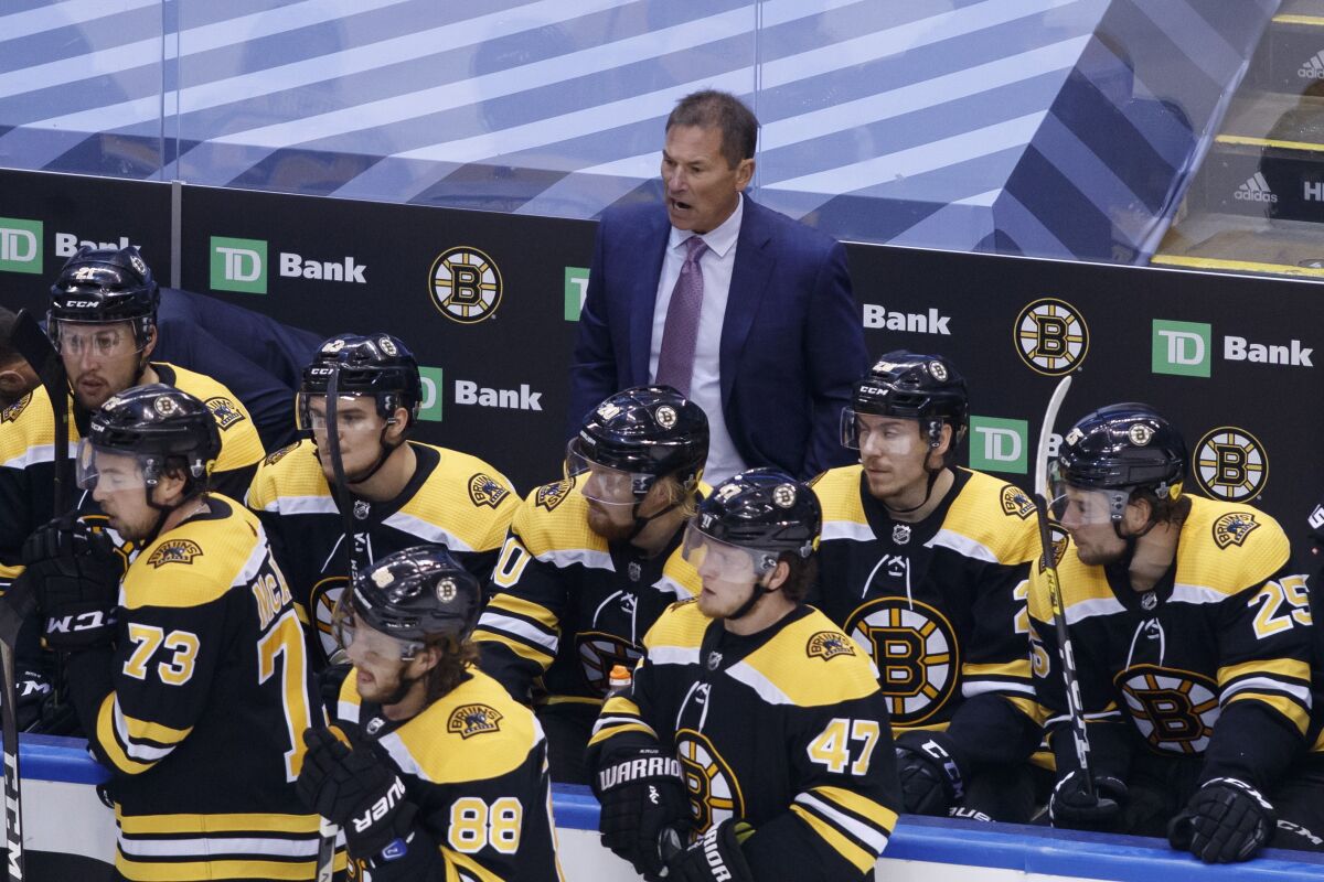 Boston Bruins head coach Bruce Cassidy, rear watches during the third period of an NHL hockey Stanley Cup playoff game against the Tampa Bay Lightning in Toronto, Saturday, Aug. 29, 2020. (Cole Burston/The Canadian Press via AP)
