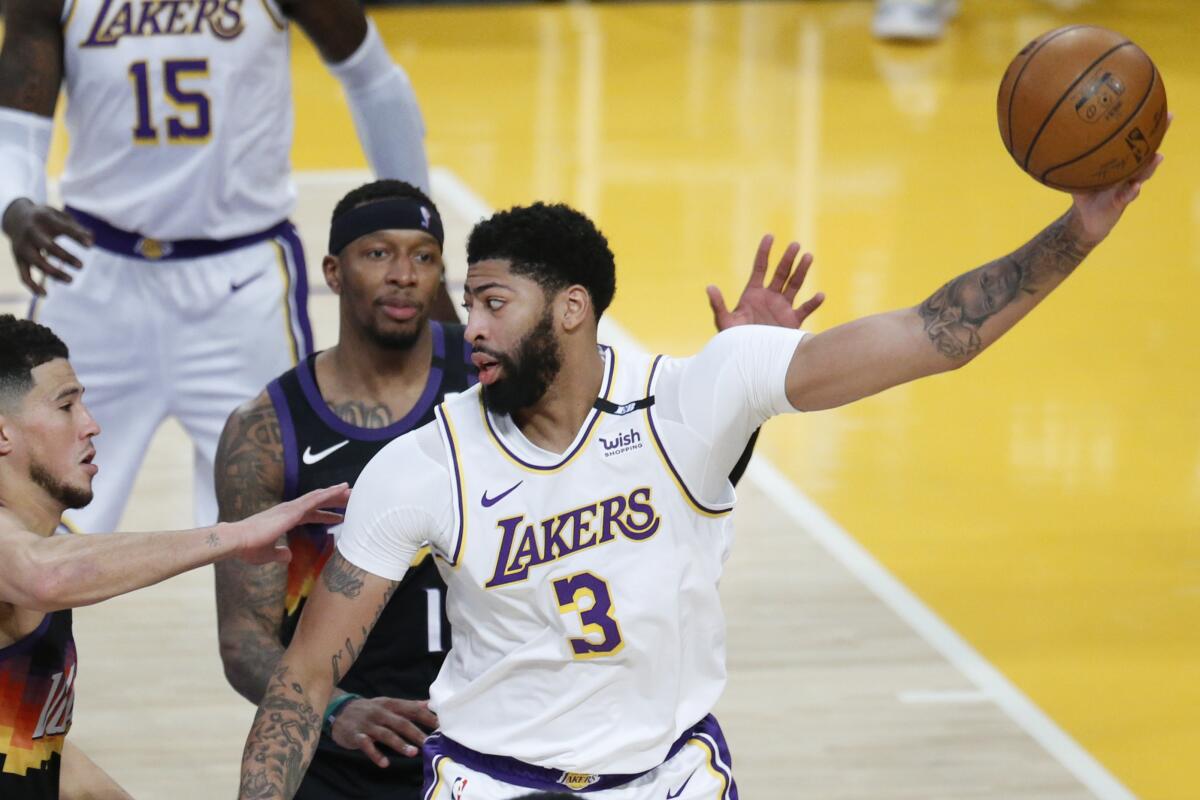 Lakers forward Anthony Davis is guarded by Phoenix Suns guard Devin Booker and forward Torrey Craig in the first quarter.