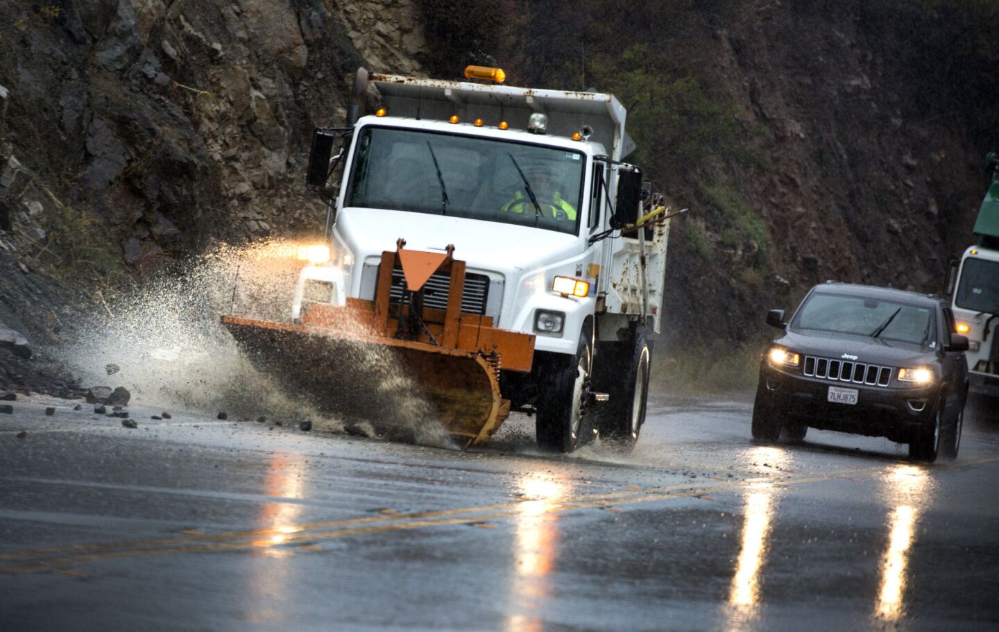 A Los Angeles County Public Works plow removes rocks from rain-soaked Malibu Canyon Road.