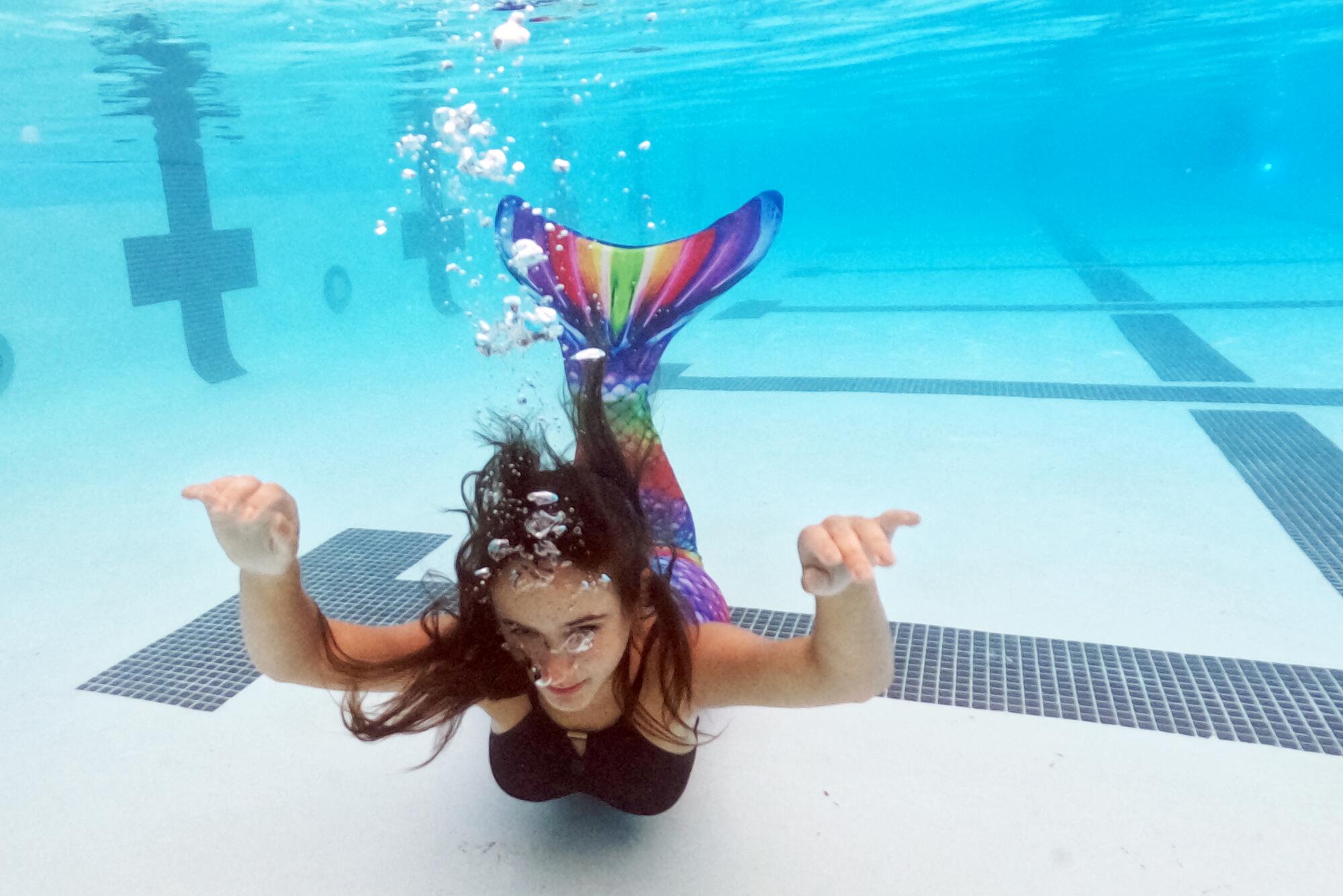 Emily Jordan demonstrates how to sink to the bottom of the pool as a mermaid.