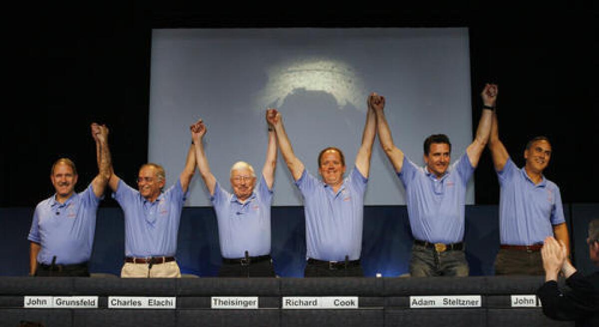 A proud lead team of John Grunsfield, Charles Elachi, Pete Theisinger, Richard Cook, Adam Steltzner and John Grotzinger, triumphantly raise their hands at JPL at the post landing press conference in 2012 with the principals who successfully landed the Mars Rover Curiosity. The rover just passed one year on the planet.