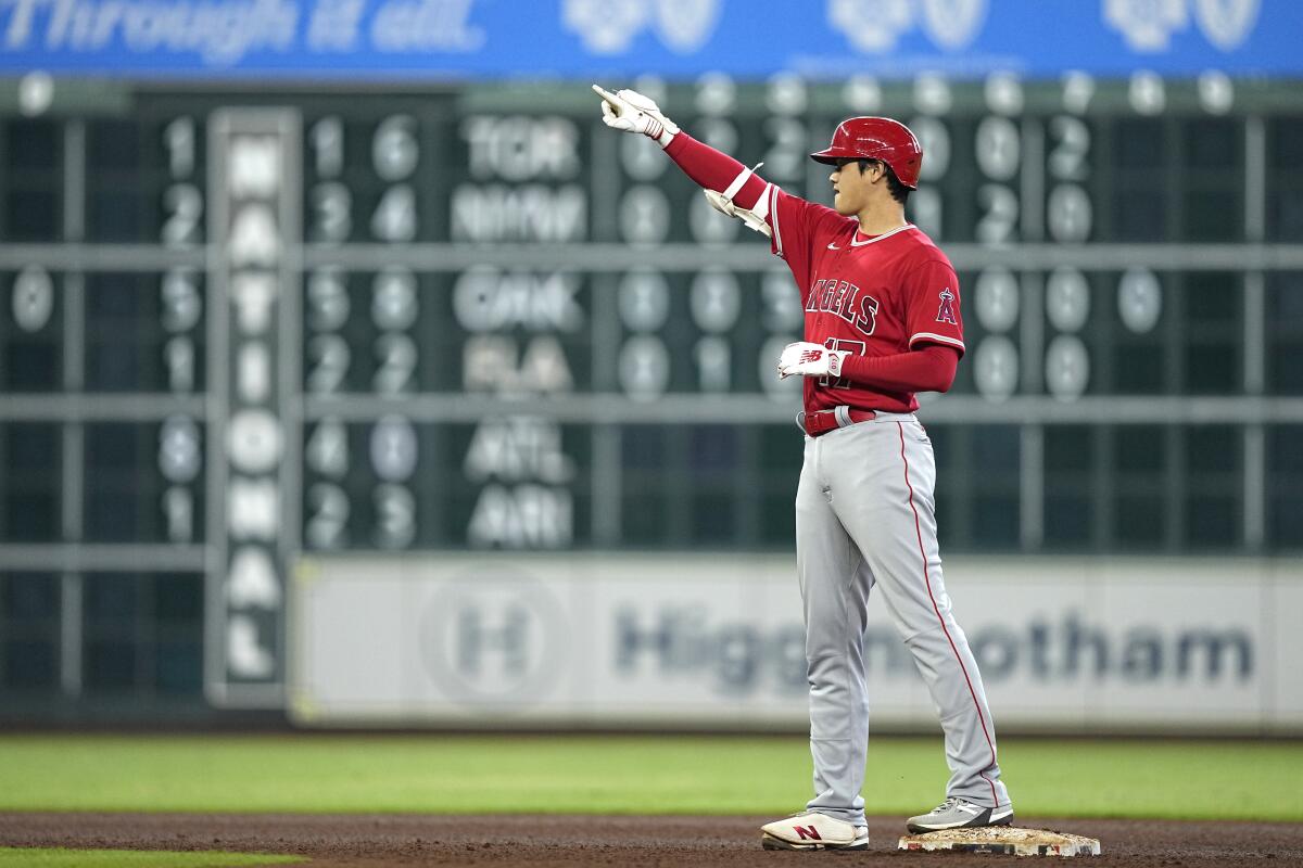 Angels star Shohei Ohtani points up while standing on a base.